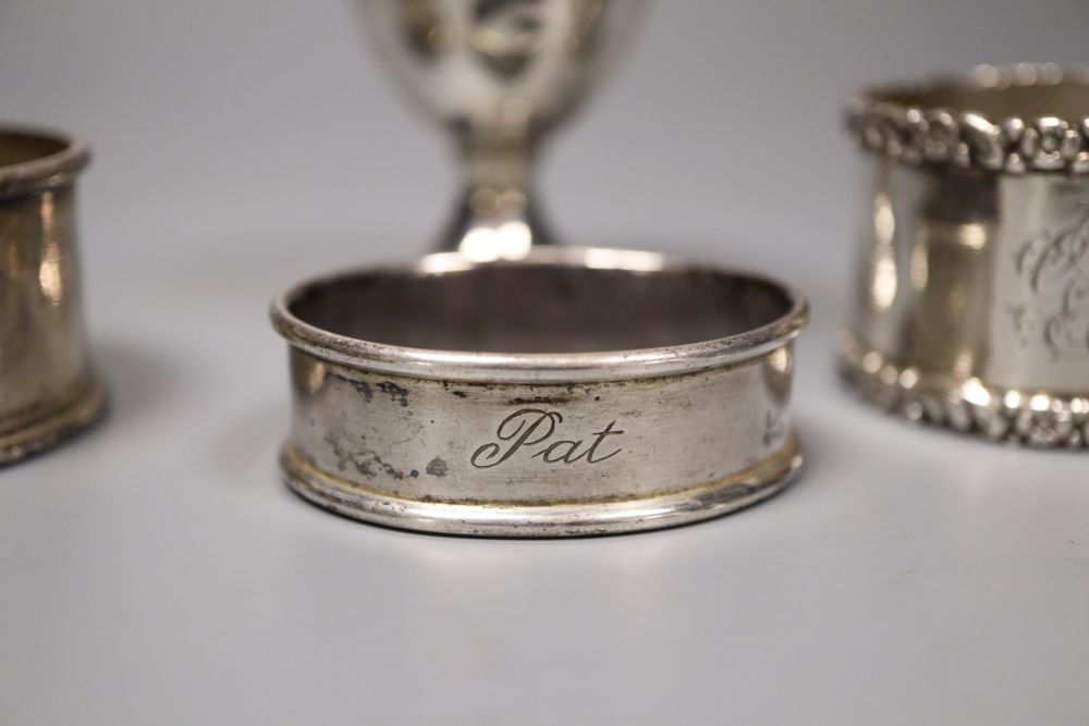 A pair of silver napkin rings, four other silver napkin rings and a small plated trophy cup.